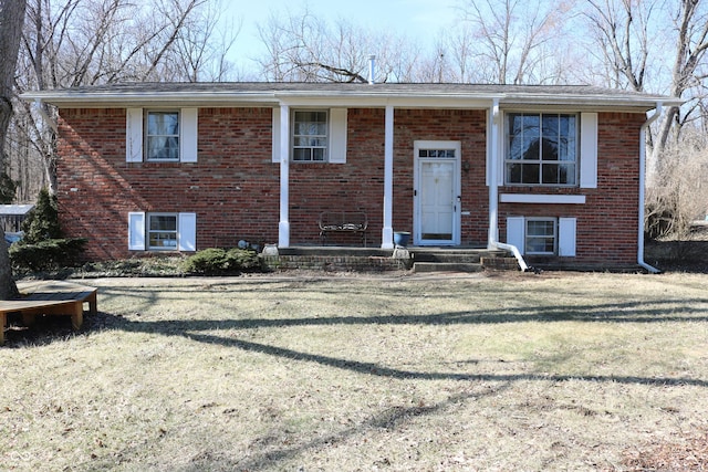 raised ranch featuring a front yard and brick siding