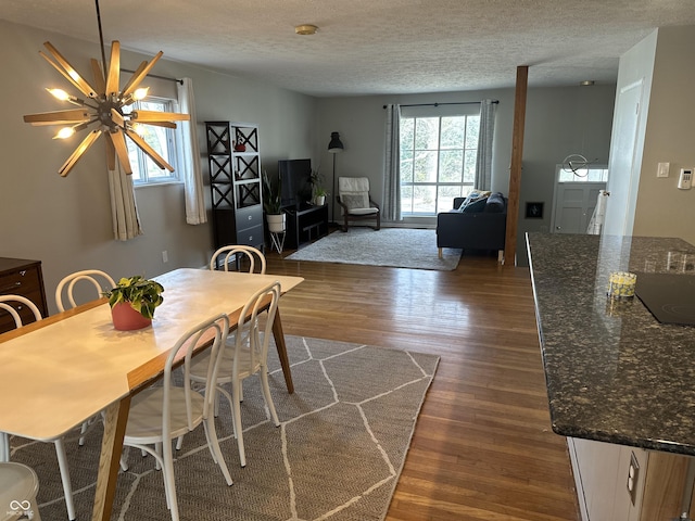 dining space featuring dark wood-style floors, a textured ceiling, and a ceiling fan