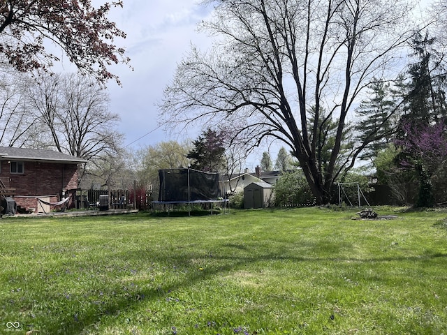 view of yard featuring a wooden deck, a storage unit, an outdoor structure, and a trampoline