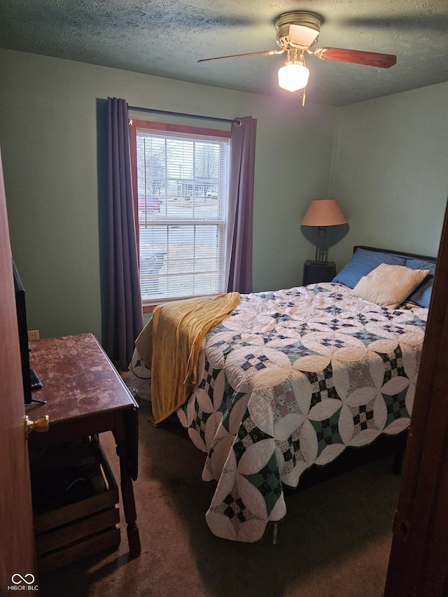 carpeted bedroom featuring ceiling fan and a textured ceiling