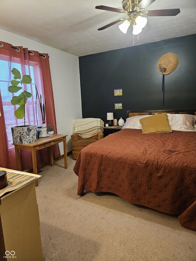 carpeted bedroom featuring ceiling fan and a textured ceiling