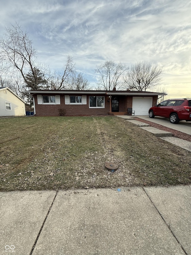 single story home with a garage, concrete driveway, brick siding, and a front lawn