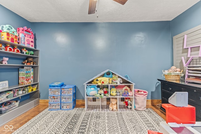 playroom featuring hardwood / wood-style floors, a textured ceiling, and ceiling fan