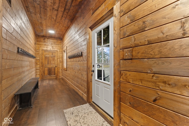 hall featuring dark wood-type flooring, wood ceiling, and wooden walls