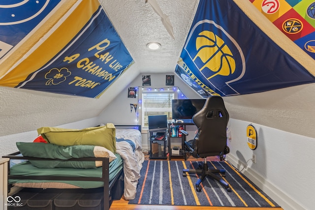 interior space with lofted ceiling, wood-type flooring, and a textured ceiling