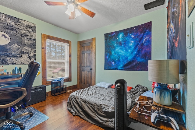 bedroom featuring hardwood / wood-style flooring, ceiling fan, and a textured ceiling