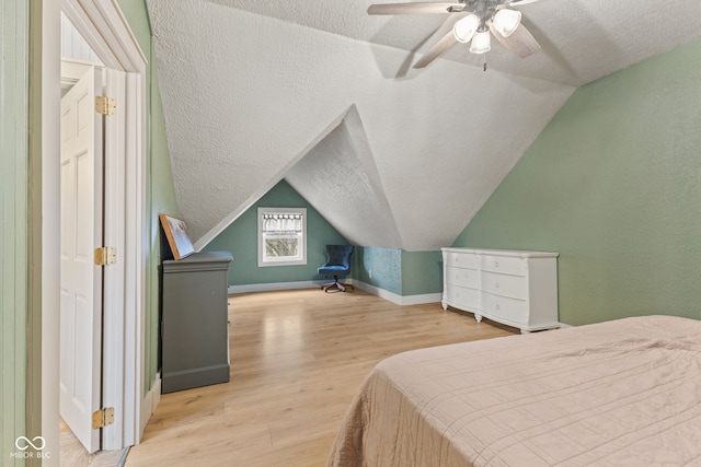 bedroom with lofted ceiling, a textured ceiling, and light wood-type flooring