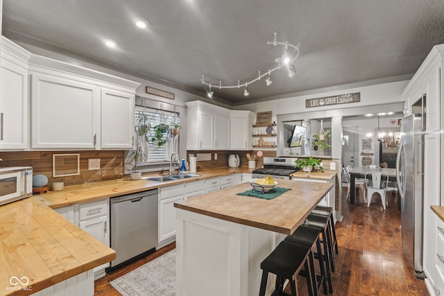 kitchen with wood counters, sink, white cabinets, and appliances with stainless steel finishes