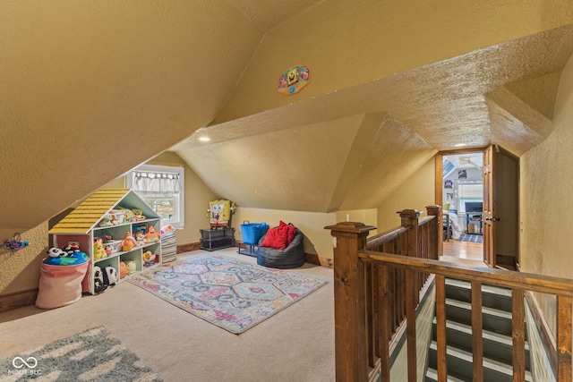 recreation room with lofted ceiling, carpet, and a textured ceiling