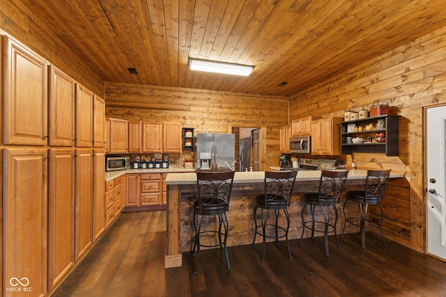 kitchen with a kitchen island, appliances with stainless steel finishes, a breakfast bar area, and dark hardwood / wood-style flooring