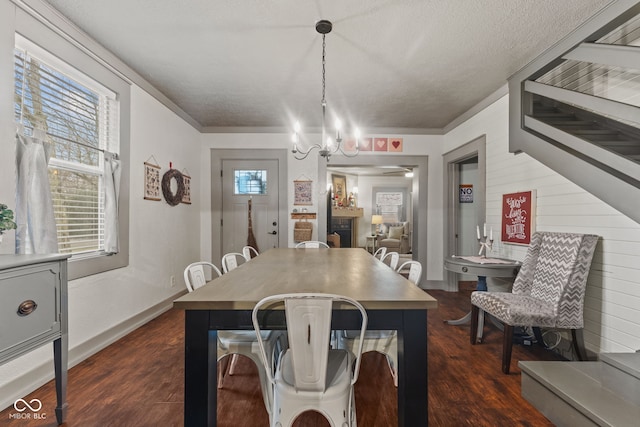 dining area with dark hardwood / wood-style floors, a textured ceiling, a chandelier, and wood walls