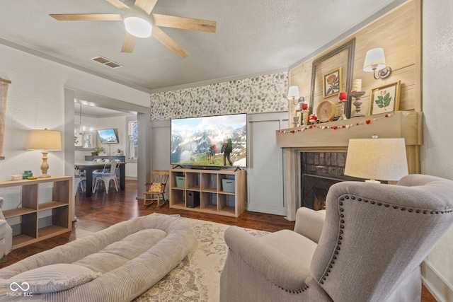 living room with dark hardwood / wood-style flooring, ceiling fan with notable chandelier, ornamental molding, and a textured ceiling