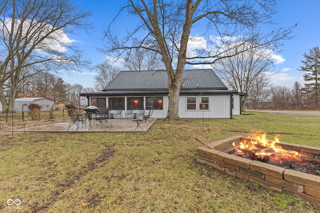 back of house with a fire pit, a patio area, and a lawn