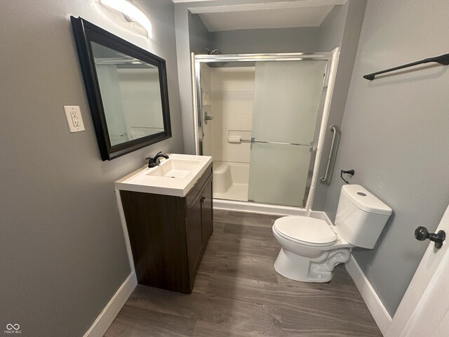 bathroom with wood-type flooring, toilet, an enclosed shower, and vanity