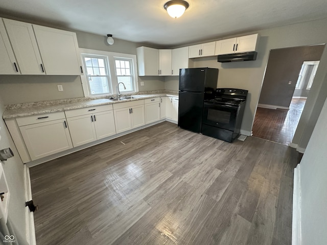 kitchen with wood-type flooring, sink, white cabinets, light stone counters, and black appliances