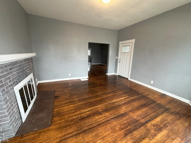 unfurnished living room featuring a brick fireplace and dark hardwood / wood-style flooring