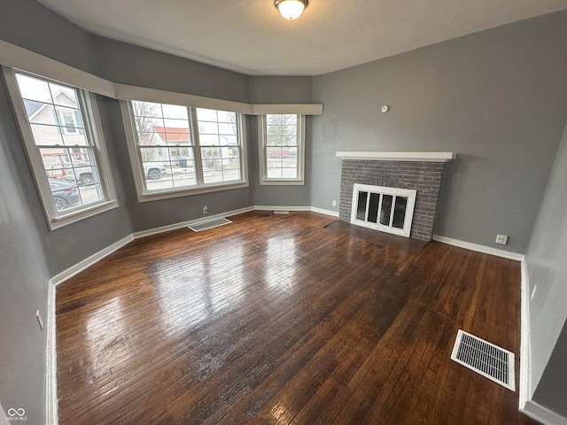 unfurnished living room featuring a brick fireplace and dark hardwood / wood-style floors