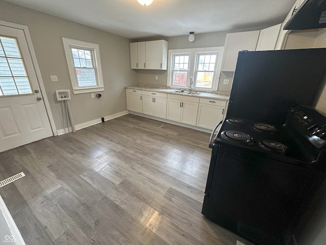 kitchen featuring sink, white cabinets, light hardwood / wood-style floors, and black / electric stove