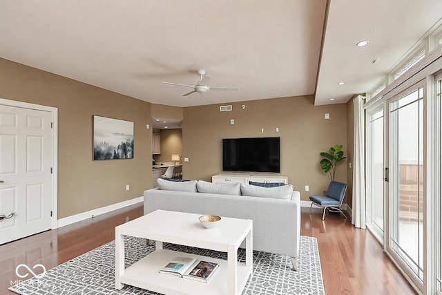 living room with a ceiling fan, visible vents, light wood-style flooring, and baseboards