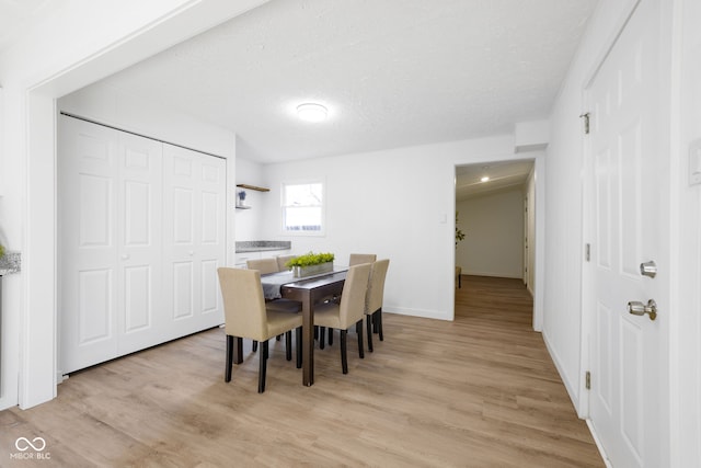 dining space with a textured ceiling and light hardwood / wood-style flooring