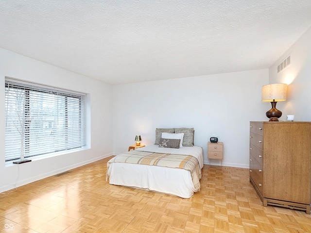 bedroom with light parquet flooring and a textured ceiling