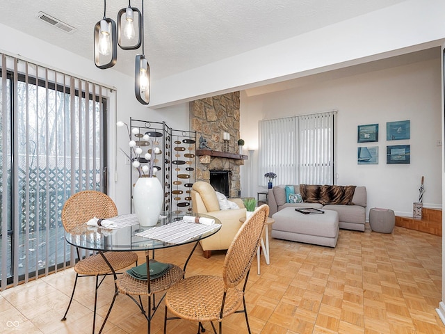 dining space featuring light parquet floors, a fireplace, and a textured ceiling