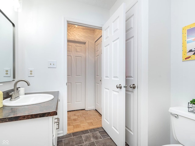 bathroom featuring vanity, parquet flooring, and toilet