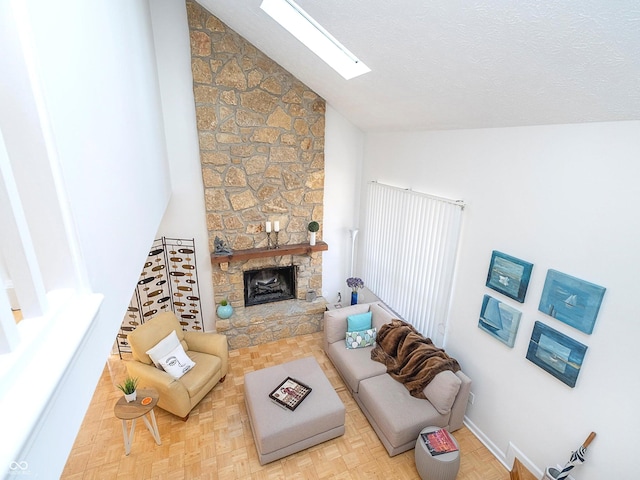 living room with a stone fireplace, a skylight, high vaulted ceiling, and light parquet floors