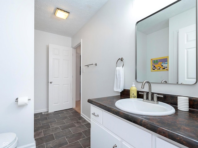 bathroom featuring vanity, toilet, and a textured ceiling