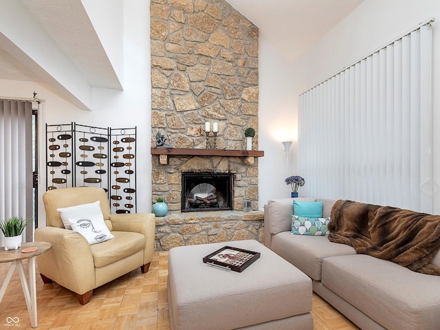 living room featuring light parquet flooring, a stone fireplace, and high vaulted ceiling