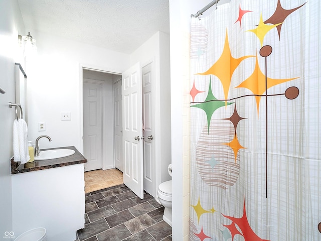 bathroom featuring a shower with curtain, vanity, a textured ceiling, and toilet