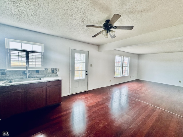 interior space featuring ceiling fan, sink, dark wood-type flooring, and a textured ceiling