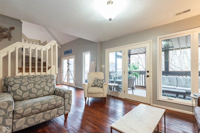 living room featuring lofted ceiling, dark hardwood / wood-style floors, and a textured ceiling