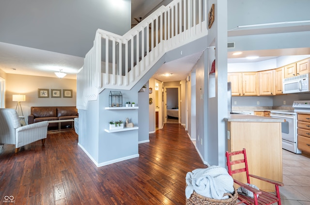 kitchen with white appliances, dark wood-type flooring, a towering ceiling, and light brown cabinets