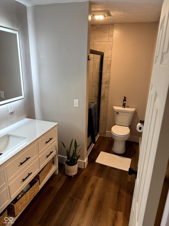 bathroom with wood-type flooring, vanity, a textured ceiling, and a shower with shower door