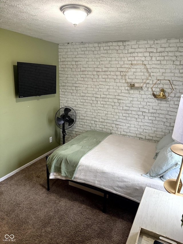 carpeted bedroom with a textured ceiling and brick wall