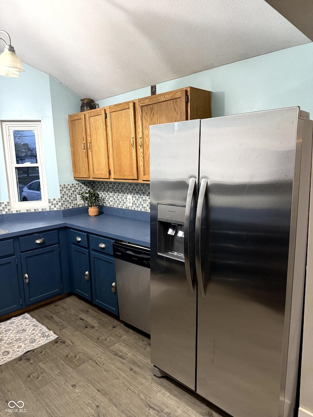 kitchen featuring hardwood / wood-style flooring, appliances with stainless steel finishes, tasteful backsplash, a textured ceiling, and vaulted ceiling