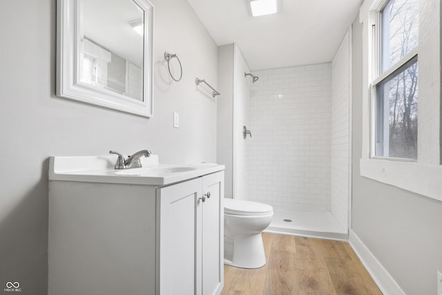 bathroom featuring hardwood / wood-style flooring, vanity, toilet, and a tile shower