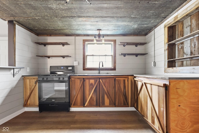 kitchen with sink, wooden walls, dark hardwood / wood-style flooring, and black range with gas cooktop