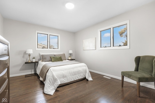 bedroom with multiple windows and dark hardwood / wood-style floors