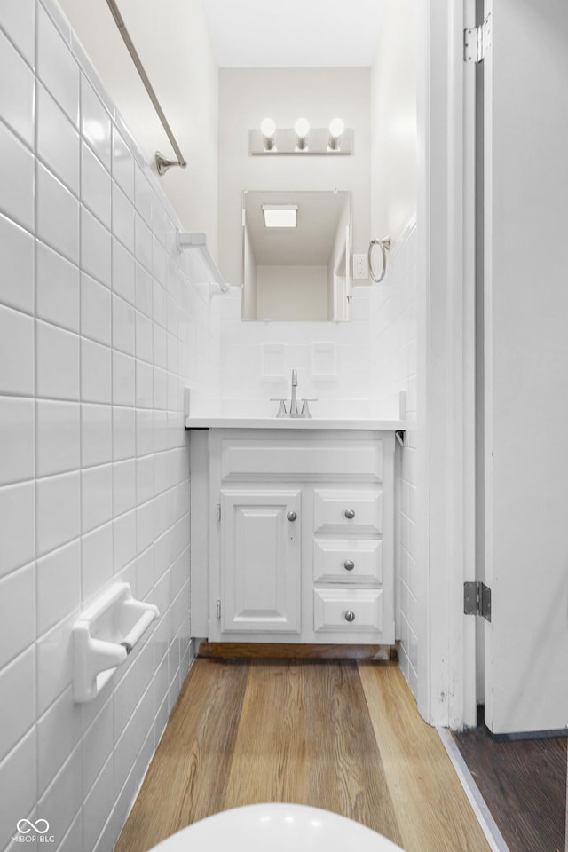 bathroom featuring vanity, wood-type flooring, and tile walls