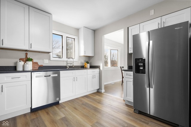 kitchen featuring light wood-type flooring, plenty of natural light, white cabinets, and appliances with stainless steel finishes