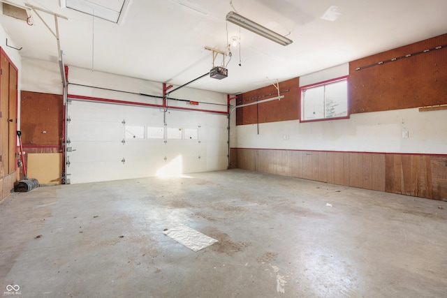 garage featuring a garage door opener and wood walls