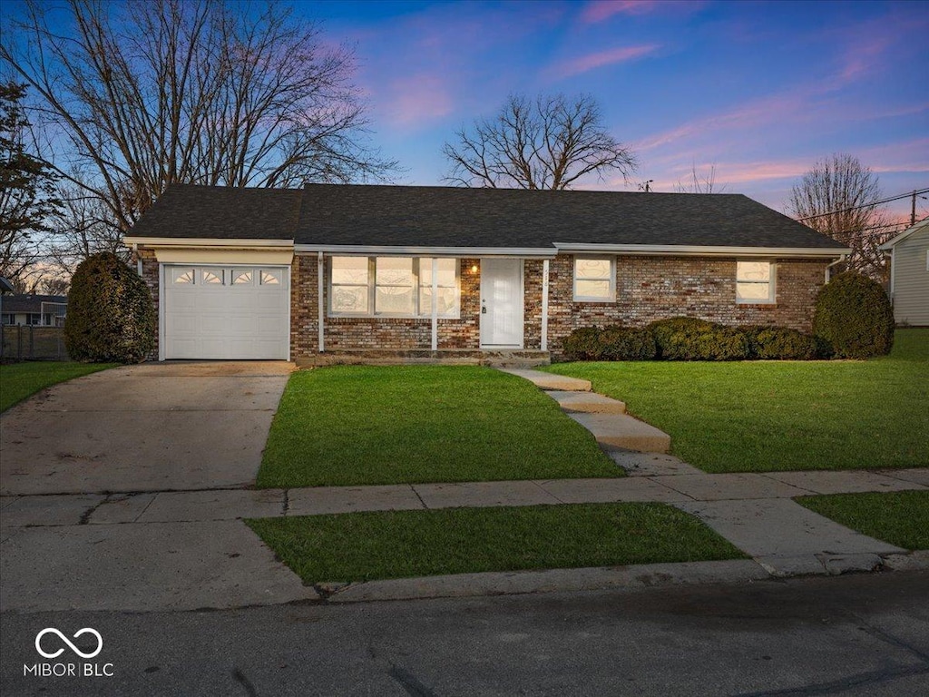 single story home featuring a garage and a yard