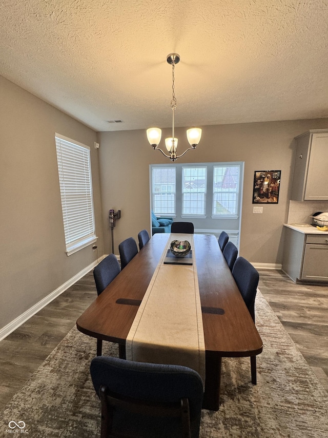 dining space featuring dark hardwood / wood-style flooring, a notable chandelier, and a textured ceiling