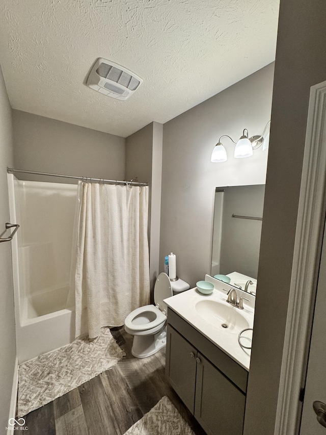 full bathroom featuring shower / tub combo with curtain, wood-type flooring, vanity, toilet, and a textured ceiling