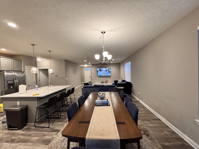 dining room with dark hardwood / wood-style flooring, a chandelier, and a textured ceiling