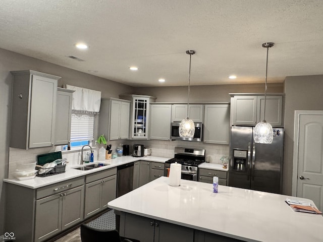 kitchen with gray cabinetry, sink, hanging light fixtures, and appliances with stainless steel finishes