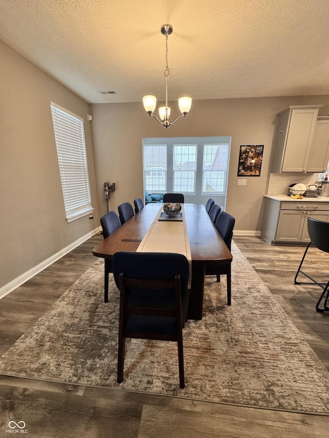 dining space with hardwood / wood-style flooring, a textured ceiling, and a chandelier