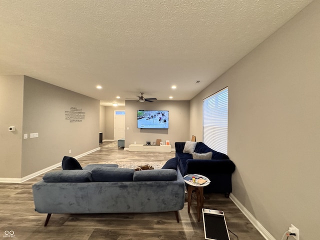 living room with hardwood / wood-style flooring, ceiling fan, and a textured ceiling